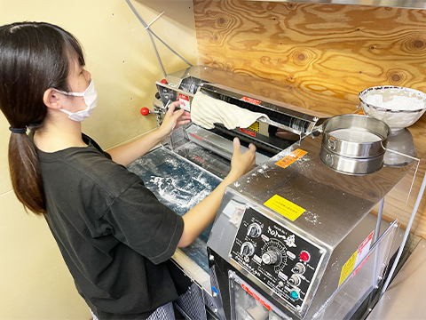 製麺機で製麺する女性