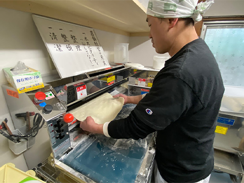 製麺機で麺を作る店主