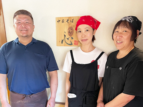 看板の前で笑う3人のスタッフ